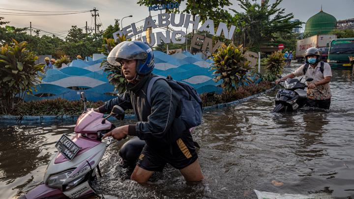 Sejumlah  pekerja mendorong motornya menembus banjir limpasan air laut ke daratan atau rob yang merendam kawasan Pelabuhan Tanjung Emas Semarang, Jawa Tengah, Senin, 23 Mei 2022. ANTARA FOTO/Aji Styawan
