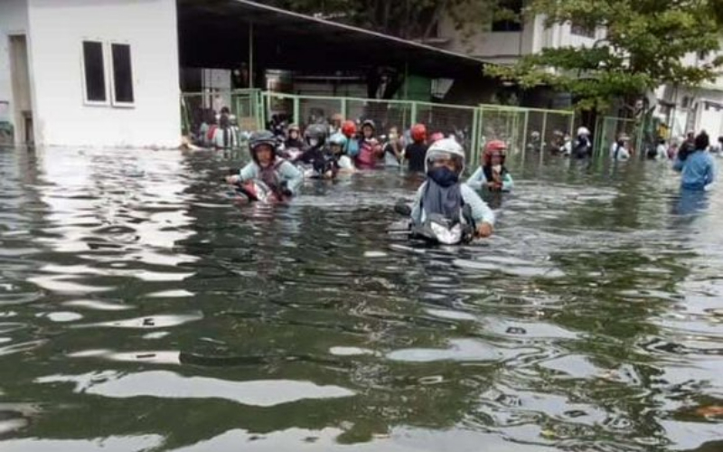 Foto pekerja pabrik mendorong motor di tengah banjir rob semarang/Twitter-AdiyatJatiW