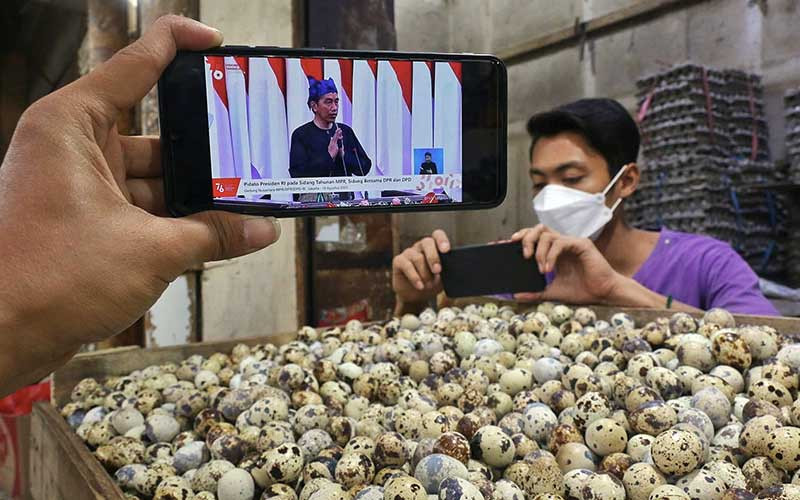 Pedagang menyaksikan Presiden Joko Widodo menyampaikan pidato dalam Sidang Tahunan MPR Tahun 2021 melalui live streaming di Jakarta, Senin (16/8/2021). Dalam kesempatan tersebut, Jokowi menyampaikan sejumlah poin penting terkait kesehatan dan penanganan pandemi Covid-19. Bisnis/Eusebio Chrysnamurti