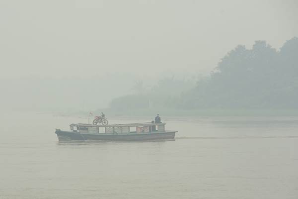 Sebuah kapal motor melintasi Sungai Kapuas yang diselimuti kabut asap tebal di Kabupaten Kubu Raya, Kalbar, Jumat (25/9). - Antara