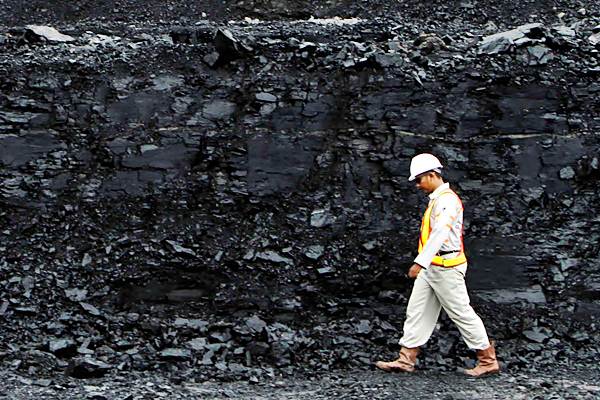 Pekerja berjalan di dekat timbunan batubara - REUTERS/Yusuf Ahmad