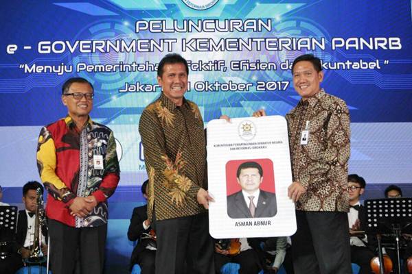 Direktur PT Bank Rakyat Indonesia Tbk Kuswiyoto (kanan), secara simbolis menyerahkan kartu e-Karpeg kepada Menteri Pendayagunaan Aparatur Negara dan Reformasi Birokrasi (PANRB) Asman Abnur (tengah), disaksikan Sekretaris Kementerian Dwi Wahyu Atmaji, disela-sela peluncuran e-Government Kementerian PANRB di Jakarta, Rabu (4/10). - JIBI/Dedi Gunawan 