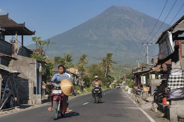 Warga melintas di jalan Desa Culik yang berjarak sekitar 10 km dari Gunung Agung, Karangasem, Bali, Jumat (29/9). - ANTARA/Nyoman Budhiana