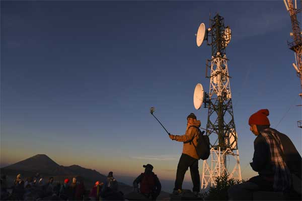 Wisatawan menikmati pemandangan Gunung Bromo dengan latar belakang Base Transceiver Station (BTS) Telkomsel di penanjakan satu Probolinggo, Jawa Timur, Jumat (19/5). - Antara/Zabur Karuru