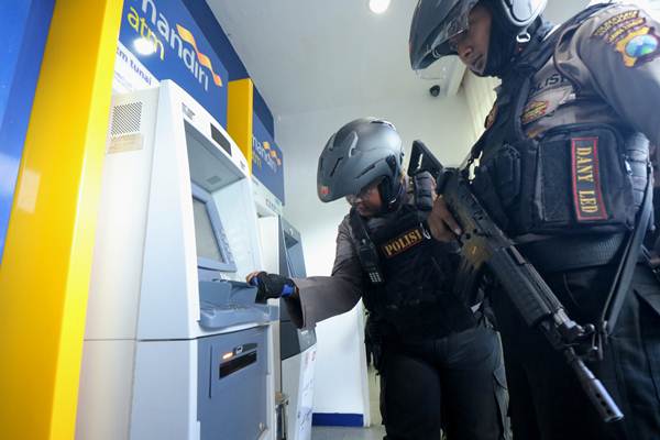 Polisi memeriksa mesin Anjungan Tunai Mandiri (ATM) Bank Mandiri, guna mengantisipasi kejahatan 'skimming', di Surabaya, Jawa Timur, Selasa (20/3/2018). - ANTARA/Didik Suhartono