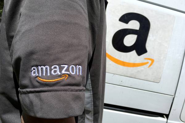 Seorang pengemudi Amazon.com Inc berdiri di samping truk di Los Angeles, California, Amerika Serikat. - Reuters