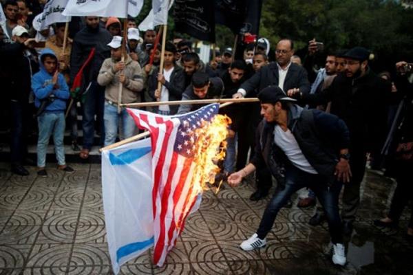 Warga Palestina membakar bendera Israel dan Amerika Serikat dalam sebuah demonstrasi terhadap niat Amerika Serikat memindahkan kedubes mereka ke Yerusalem dan mengenali Yerusalem sebagai ibukota Israel, di Kota Gaza, Rabu (6/12/2017).  - Reuters