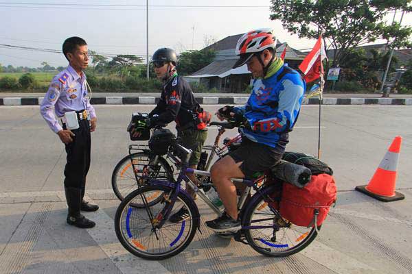 Pemudik menggunakan sepeda meminta petunjuk arah kepada petugas Dishub saat melintas di jalur Pantura Losarang, Indramayu, Jawa Barat, Jumat (8/6/2018). - ANTARA/Dedhez Anggara
