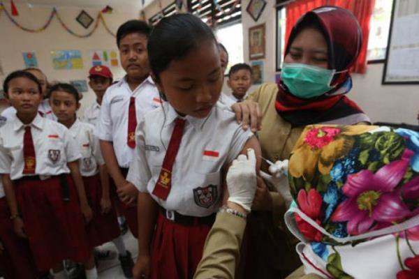 Petugas medis memberikan imunisasi difteri kepada murid sekolah dasar. - Antara