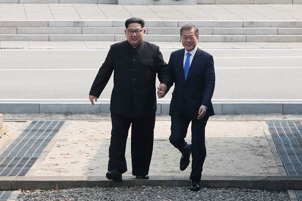 Pemimpin Korea Utara Kim Jong Un (kiri) bergandengan tangan dengan Presiden Korea Selatan Moon Jae-in saat pertemuan di desa gencatan senjata Panmunjom, Korea Selatan, Jumat (27/4/2018). - Reuters