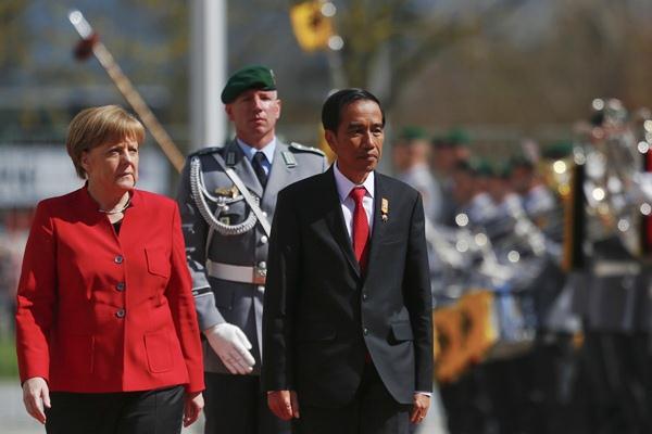 Presiden Joko Widodo (kanan) dan Kanselir Jerman Angela Merkel memeriksa pasukan, saat upacara penyambutan kedatangan Jokowi di Berlin, Jerman, Senin (18/4). - REUTERS/Hannibal Hanschke