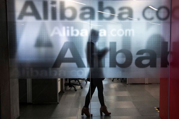 Seorang karyawan terlihat di balik dinding kaca dengan logo Alibaba di kantor pusat perusahaan itu di pinggiran Hangzhou, Provinsi Zhejiang, China. - Reuters