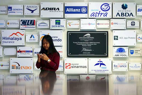 Karyawan berdiri di dekat logo beberapa perusahaan asuransi di kantor Asosiasi Asuransi Umum Indonesia (AAUI) di Jakarta. - JIBI/Nurul Hidayat