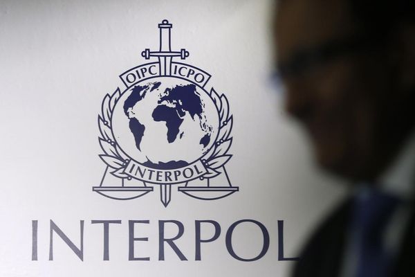 Seorang pria berjalan melewati logo Interpol di Singapura pada 2014. - Reuters/Edgar Su