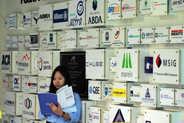 Karyawati berdiri di dekat logo beberapa perusahaan asuransi di kantor Asosiasi Asuransi Umum Indonesia di Jakarta, Senin (8/1). - JIBI/Dwi Prasetya