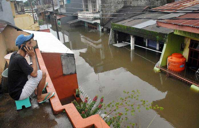 Warga menelpon di atas rumahnya saat banjir di Kecamatan Manggala, Makassar, Sulawesi Selatan, Rabu (23/1/2019). Akibat diguyur hujan dalam beberapa hari sejumlah daerah di Makassar terendam banjir. - ANTARA/Abriawan Abhe
