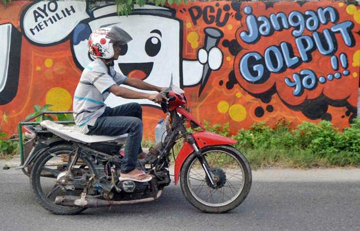 Pengendara melintas di depan mural (gambar dinding) tentang Pemilu 2019, di Jalan Samudera, Padang, Sumatra Barat, Selasa (12/2/2019). - ANTARA/Iggoy el Fitra