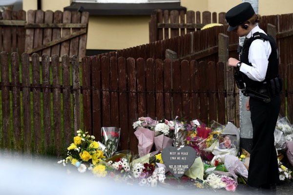 Polisi berdiri di samping tumpukan bunga yang ditujukan kepada Lyra McKee, jurnalis yang tewas ditembak dalam sebuah kerusuhan, di Londonderry, Irlandia Utara, Jumat (19/4/2019). - Reuters/Clodagh Kilcoyne
