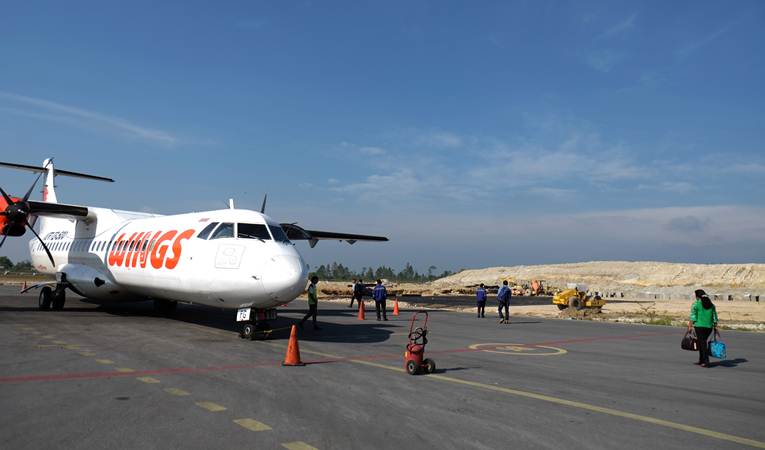 Penumpang bersiap naik ke pesawat dengan latar belakang proyek pembangunan perluasan Bandara Internasional Raja Sisingamangaraja XII (sebelumnya bernama Silangit), di Tapanuli Utara, Sumatra Utara, Selasa (19/3/2019). - ANTARA/Irsan Mulyadi