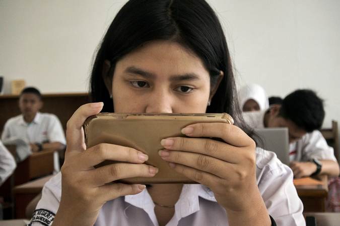 Siswi menggunakan gawai saat mengerjakan soal UASBN 2019 di SMA Negeri 9 Kota Bandung, Jawa Barat, Senin (18/3/2019). SMA Negeri 9 Kota Bandung tersebut mulai menerapkan penggunaan teknologi smart router dalam pelaksanaan UASBN. - ANTARA/Novrian Arbi
