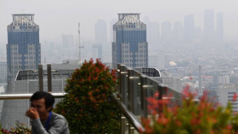 Warga beraktivitas dengan latar belakang suasana gedung bertingkat yang diselimuti asap polusi di Jakarta, Senin (29/7/2019).  - Antara