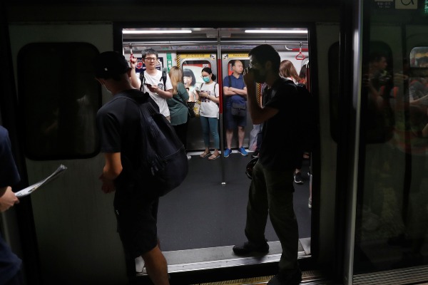 Pengunjuk rasa berdiri di pintu Mass Transit Railway (MTR) untuk mencegah kereta tersebut berangkat dan sebagai bentuk protes terhadap pemerintah setempat di Stasiun Fortress Hill, Hong Kong, China, Minggu (5/8/2019). - Reuters/Kim Kyung/Hoon