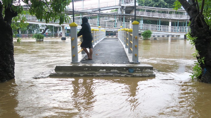 Seorang warga berada di atas jembatan Sungai Ciliwung yang meluap dan banjir menggenangi kawasan Pasar Baru di Jakarta Pusat, Kamis (2/1/2020). - ANTARA /M Risyal Hidayat