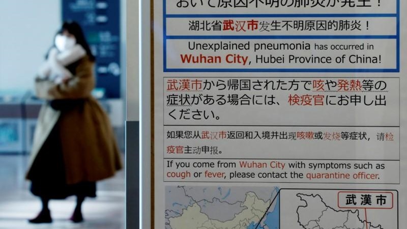 Seorang wanita mengenakan masker berjalan melewati papan pemberitahuan karantina tentang wabah virus corona di Wuhan, China di ruang kedatangan Bandara Haneda di Tokyo, Jepang, 20 Januari 2020. -  REUTERS / Kim Kyung/Hoon