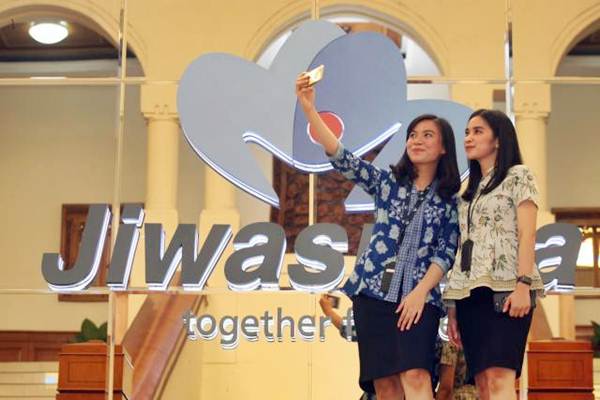 Karyawati melakukan swafoto di dekat logo PT Asuransi Jiwasraya di Jakarta, Jumat (14/9/2018). - JIBI/Dedi Gunawan