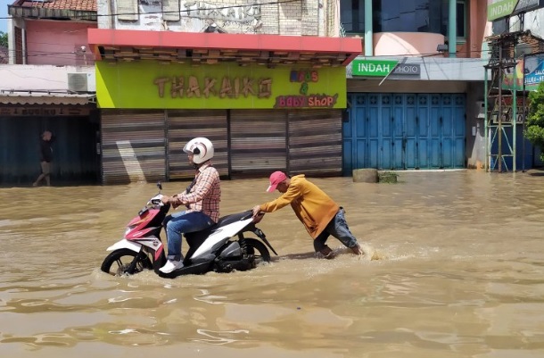 Seorang pengendara motor melintasi genangan banjir di Jalan Raya Dayeuhkolot, Kabupaten Bandung. - Antara