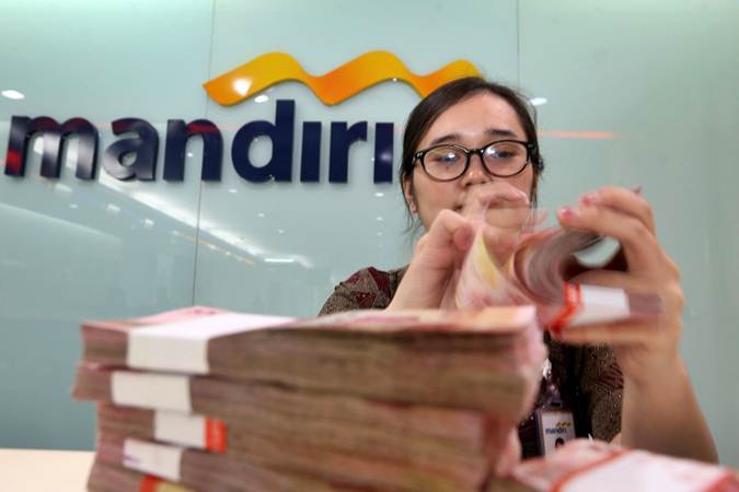 Karyawati menghitung uang pecahan Rp100.000 di salah satu kantor cabang milik Bank Mandiri, di Jakarta, Rabu (12/6/2019). - Bisnis/Nurul Hidayat