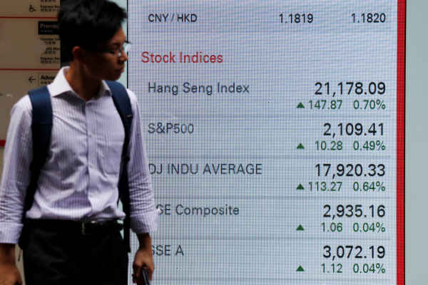 A man walks past a panel displaying stock indices of Hong Kong, U.S. and China markets, outside a bank in Hong Kong June 7, 2016. REUTERS - Bobby Yip