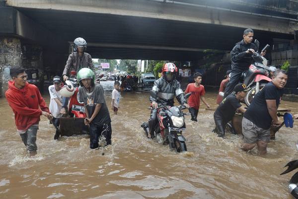 Pengendara motor menggunakan jasa angkut untuk melintasi banjir yang menggenangi bawah jembatan Tol JORR, Kali Malang, Bekasi, Jabar, Selasa (21/2). - Antara/Saptono