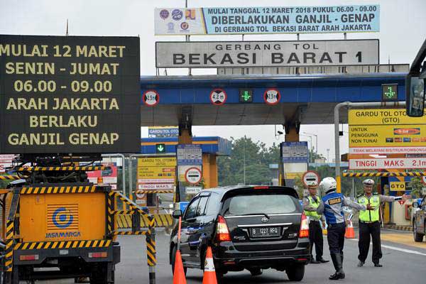 Petugas mengarahkan kendaraan roda empat berpelat nomor ganjil berputar balik keluar dari gerbang tol Bekasi Barat 1 di Bekasi, Jawa Barat, Senin (12/3). - ANTARA/Widodo S Jusuf
