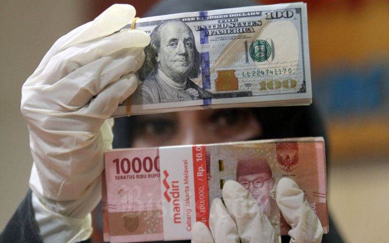 Petugas menunjukkan uang rupiah dan dolar AS di salah satu gerai penukaran mata uang asing di Jakarta, Kamis (19/3/2020). - Bisnis/Arief Hermawan P