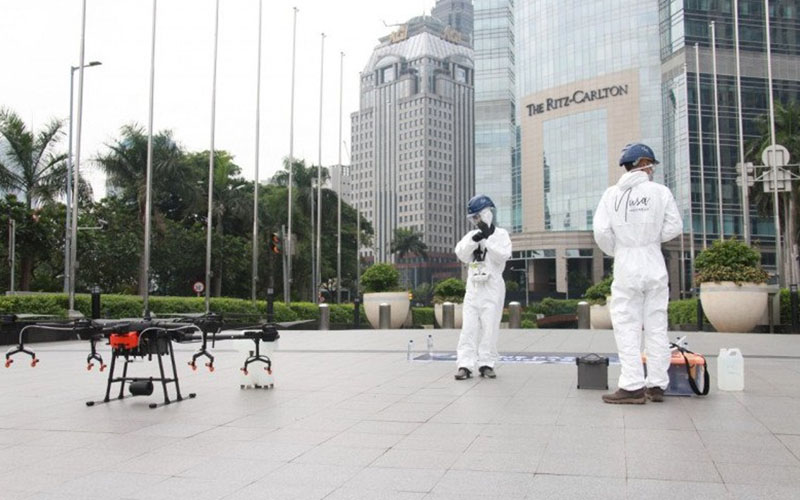 Petugas mengoperasikan drone untuk melakukan penyemprotan disinfektan di jalan protokol di Jakarta Selatan pada Jumat (27/3/2020). - Antara
