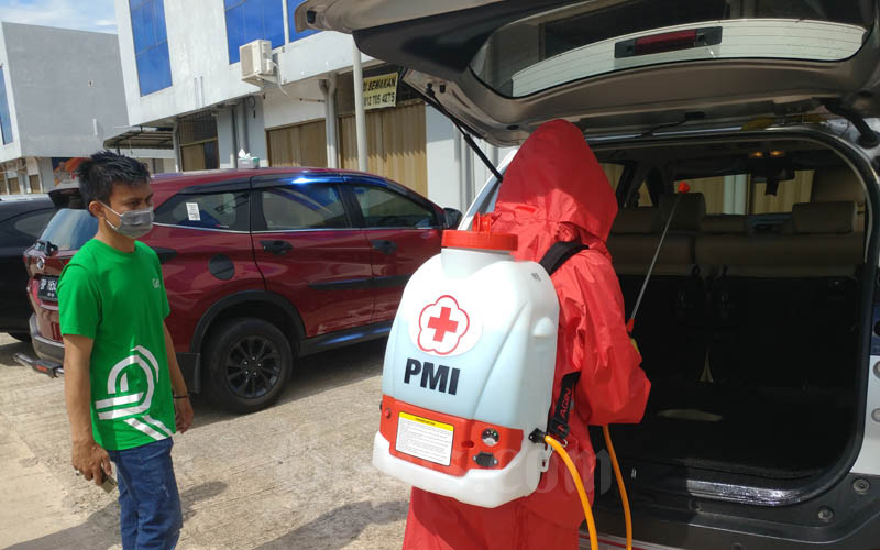 Petugas dari PMI Kota Batam ketik melakukan penyemprotan cairan desinfektan ke kendaraan mitra Grab Kota Batam pada Jumat (3/4/2020). - Bisnis/Bobi Bani.