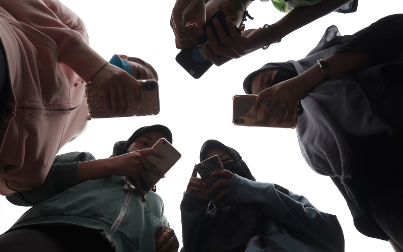 Sejumlah remaja menggunakan ponsel saat berkomunikasi di Medan, Sumatera Utara, Jumat (17/4/2020). - ANTARA FOTO/Septianda Perdana