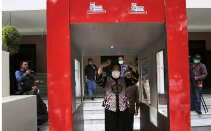 Wali Kota Surabaya Tri Rismaharini saat mencoba alat disinfektan baru penangkal Covid-19 berupa bilik yang diberi nama 'Bilik Disinfektan Trisakti' di halaman Rumah Dinas Wali Kota Surabaya, Sabtu (21/3/2020). - ANTARA Jatim