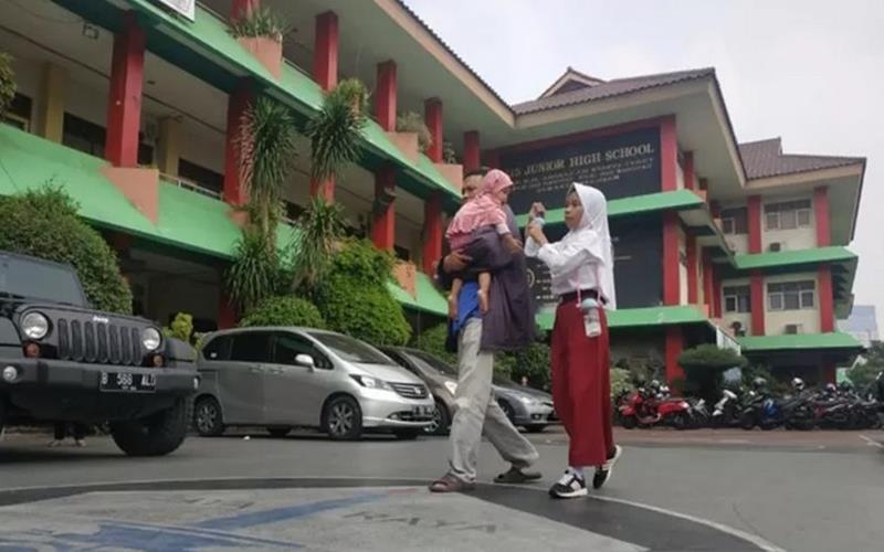 Orangtua siswa mengantarkan anaknya mendaftar sekolah di SMP 115, Jakarta, Senin (24/6/2019). - Antara