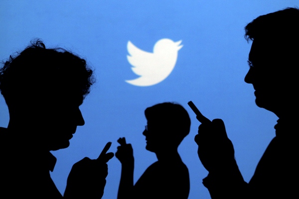 Ilustrasi orang sedang memegang ponselnya dengan latar belakang logo Twitter. - Reuters/Kacper Pempel