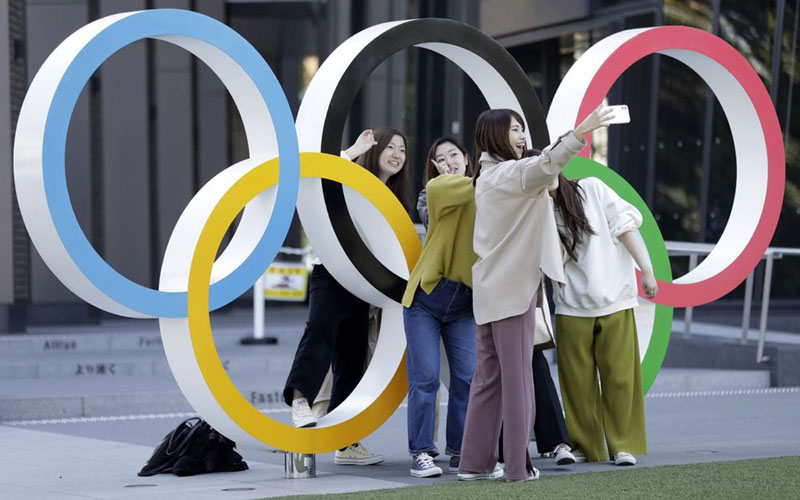 Sejumlah warga berfoto di dekat logo Olimpiade di depan Museum Olimpiade di Tokyo, Jepang, pada 11 Maret 2020./Bloomberg - Kiyoshi Ota