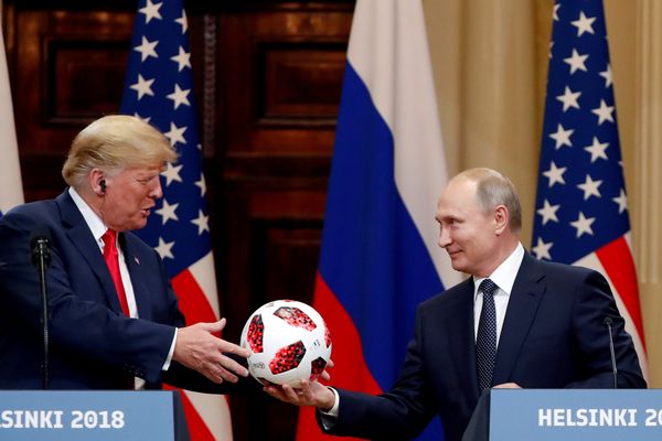 Presiden AS Donald Trump (kiri) menerima bola sepak dari Presiden Rusia Vladimir Putin (kanan) dalam konferensi pers bersama setelah keduanya bertemu membahas sejumlah isu di Helsinki, Finlandia, Senin (16/7). - Reuters/Grigoriy Dukor