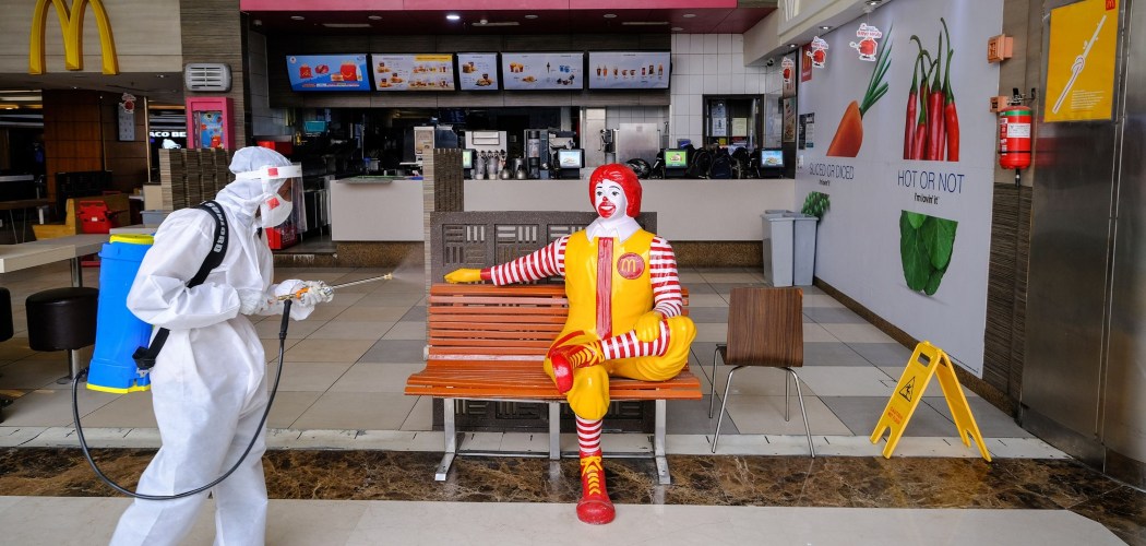 Petugas mengenakan Alat Pelindung Diri (APD) melakukan disinfektasi di restoran McDonald's di New Delhi, India, Senin (8/6/2020). - Bloomberg/T. Narayan