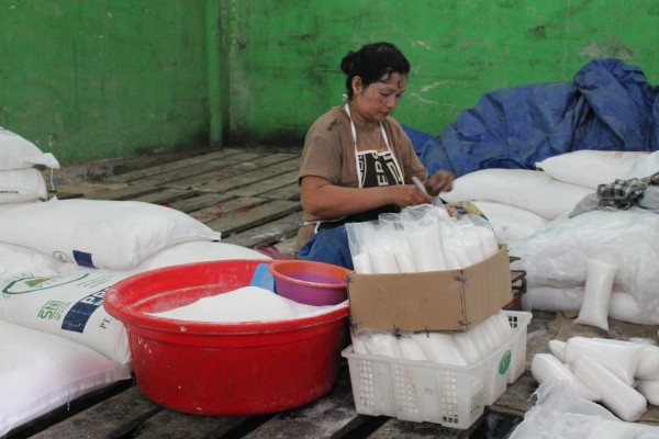 Salah satu pedagang gula dipasar tradisional sedang mengemasi gula pasir untuk dijual kembali  -  Arief Rahman