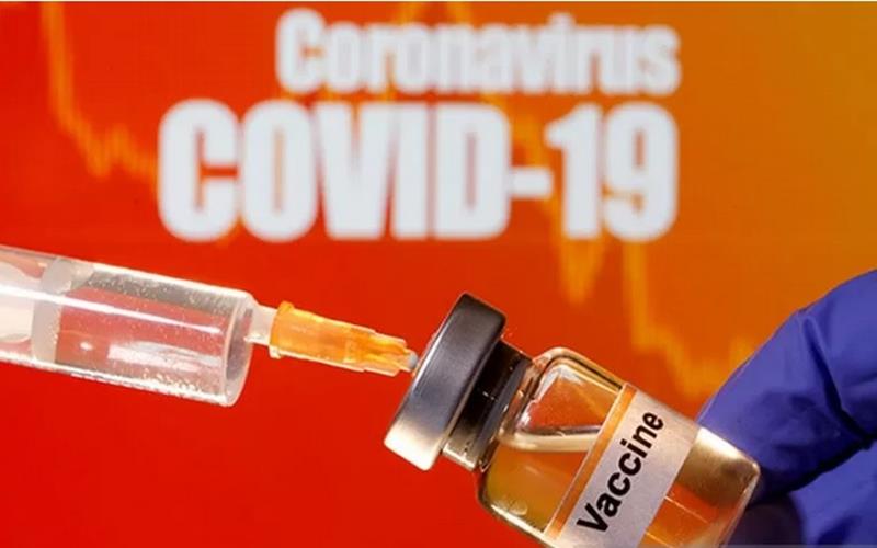 Sebuah botol kecil berlabel Vaksin diletakkan di dekat jarum suntik medis di depan tulisan Coronavirus Covid-19