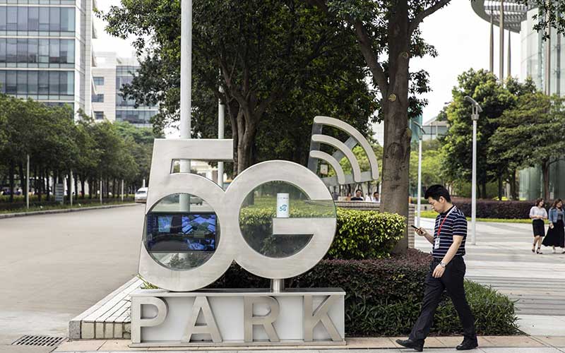Warga menggunakan smartphone berjalan melewati papan Taman 5G di markas Huawei Technologies Co. di Shenzhen, China, Rabu(22/5/2020).Bloomberg - Qilai Shen