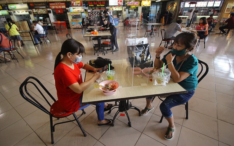 Pengunjung menikmati makanan di meja makan yang bersekat di pusat jajanan serba ada (pujasera) atau 
