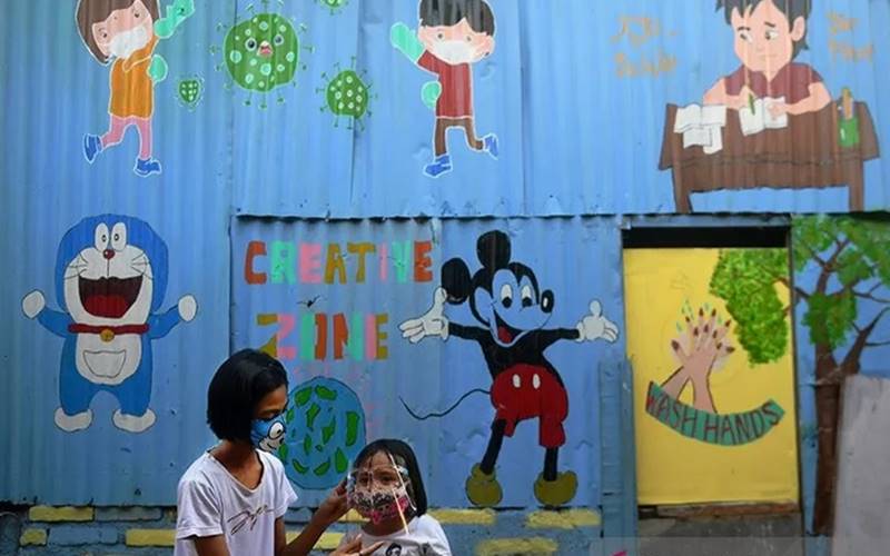 Ilustrasi - Dua orang anak menggunakan masker pelindung wajah saat bermain di depan mural bertema Covid-19 di Jakarta, Senin (27/7/2020). - Antara