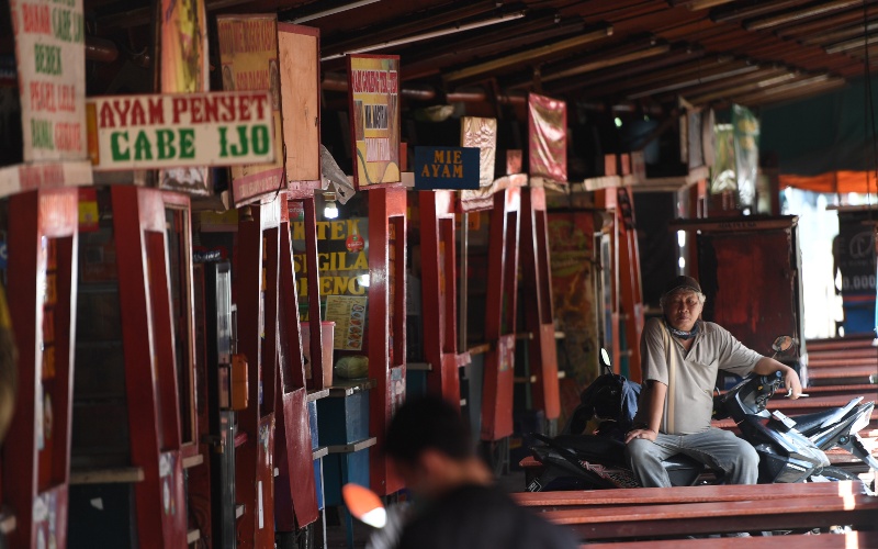 Seorang pria duduk di deretan warung kaki lima yang tutup menyusul sepinya pengunjung akibat pandemi COVID-19 di Jakarta, Kamis (2/4/2020). Minimnya aktivitas perkantoran di Jakarta akibat pandemi COVID-19 membuat sejumlah pedagang warung kaki lima memilih untuk menutup dagangannya dan mudik ke kampung halaman. - ANTARA FOTO/Akbar Nugroho Gumay